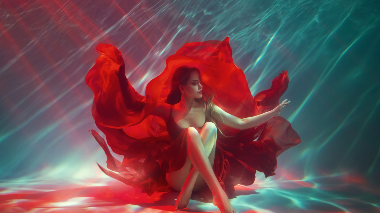 Calm relaxation meditation concept. Sexy fashion model Fantasy woman sitting under water sea, red long silk dress fabric floating. fairy girl posing in deep pool underwater shooting Art Magic light